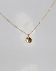 A gold chain necklace with a small, round pendant featuring the letter "A" in a cursive font.