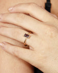 A gold ring with a dark blue, emerald-cut alexandrite gemstone