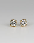 A pair of gold stud earrings with clear round sapphires