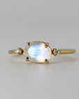 A gold ring with a large oval moonstone and two smaller diamond accents.