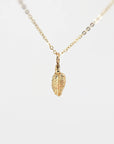 A delicate gold chain necklace with a small, detailed leaf pendant.