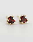 A pair of gold stud earrings with small heart-shaped red garnet gemstones.