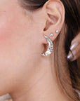 Silver crescent moon earrings with small clear stones. The earrings are hammered and have a textured finish.