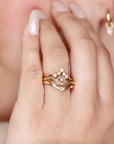 Three gold rings with diamonds. The top ring has a large round center stone and smaller diamonds on each side. The middle ring is a thin band. The bottom ring is a chevron shape with a single diamond at the point. Third band is a Curved Wedding Band or can be used as Alternative Engagement Ring.