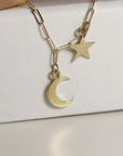 A gold chain necklace with a crescent moon and star charm.