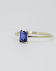 A gold ring with a blue emerald-cut sapphire gemstone.
