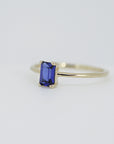A gold ring with a blue emerald-cut sapphire gemstone.