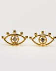 A pair of gold earrings with a small diamond in the center of each earring. The earrings are shaped like an eye with a circle around the diamond.
