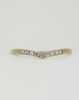A delicate gold band with a chevron shape, adorned with a row of small, sparkling diamonds.
