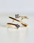 A gold ring with two small, clear CZ diamonds. The ring is twisted and has a delicate design.