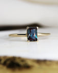 A gold ring with a dark blue, emerald-cut alexandrite gemstone