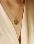 A white gold necklace with a round pendant featuring five small diamonds set in a circular pattern.