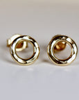 A pair of gold hammered circle stud earrings. The earrings are simple and elegant, and would make a great gift for any occasion.