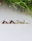 Two pairs of small, geometric earrings in 14k Gold. The earrings are in the shape of a chevron. The earrings are in three different colors: rose gold, and yellow gold.