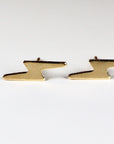A pair of gold lightning bolt stud earrings.