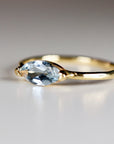 A delicate gold ring with a light blue marquise-shaped aquamarine gemstone.