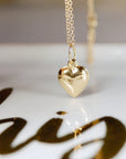 A gold heart pendant necklace with a delicate chain. The pendant is a simple, classic heart shape.