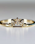 A delicate gold ring with a row of five small, diamond-shaped stones set in a leaf-like design.
