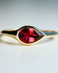 A gold ring with a pear-shaped tourmaline gemstone set in the center.