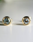 Round aquamarine bezel stud earrings in 14k solid gold, displayed on a white background as March birthstone jewelry.