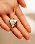 A gold heart-shaped locket necklace with a delicate floral design engraved on the front.