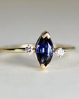 Diamond & Sapphire Engagement Ring A gold ring with a marquise-shaped sapphire gemstone and two smaller round diamonds on either side.