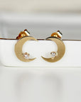 A pair of gold crescent moon earrings with a small diamond accent in the center of each moon.