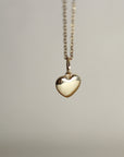 A gold heart-shaped pendant hangs from a delicate gold chain.