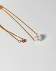 A gold Pearl necklace. A gold chain necklace with a large, white, baroque pearl pendant.