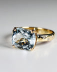A gold ring with a large, light blue aquamarine gemstone and small diamonds set in the band.