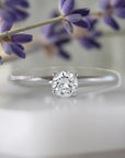 A simple white gold band engagement ring with a single round brilliant cut diamond.