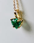 A gold chain necklace with a heart-shaped emerald green emerald pendant.