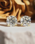 A pair of gold stud earrings with round, clear diamonds.