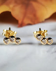 14k gold curved ear climber earrings with three bezel-set CZ stones in a trio design, shown on a white background.