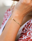 A gold bracelet with a delicate chain and small round discs.