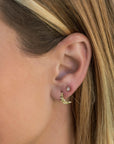 A pair of gold earrings, one is a crescent moon shape and the other is a small round stud with a clear stone.