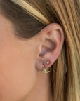 A pair of gold earrings, one is a crescent moon shape and the other is a small round stud with a clear stone.