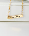 Gold bar necklace with Roman numerals VI.VIII.MMXXIV engraved. The necklace features a delicate gold chain and a rectangular bar pendant. The pendant has a subtle, matte finish and the numbers are precisely engraved. This minimalist gold bar necklace is perfect for adding a touch of elegance to any outfit.