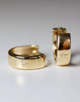 A pair of gold hoop earrings with a small diamond star in the center of each hoop.