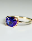 A gold ring with a large oval-shaped purple amethyst gemstone.
