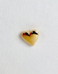 A small, gold heart-shaped earring.