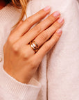 Model wearing a gold, wavy, simple wedding band ring.