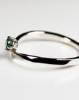 A 14k White gold ring with a single, round, green sapphire gemstone set in the center. The ring is simple and elegant.