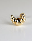 A gold croissant shaped earring. The earring is a simple design with a smooth finish.