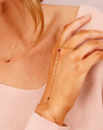 Gold chain bracelet with red garnet gemstone accents. The bracelet is designed to wrap around the wrist and finger.