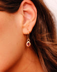 Gold dangle earrings with a small pink teardrop tourmaline gemstone.