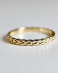 A gold braided ring with a smooth, polished finish.
