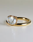 A gold ring with a clear oval gemstone set in a delicate wire cage.