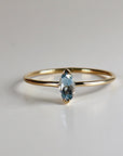 A delicate gold ring with a marquise-shaped aquamarine gemstone.