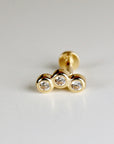 Gold body jewelry with three clear round stones in a row.
